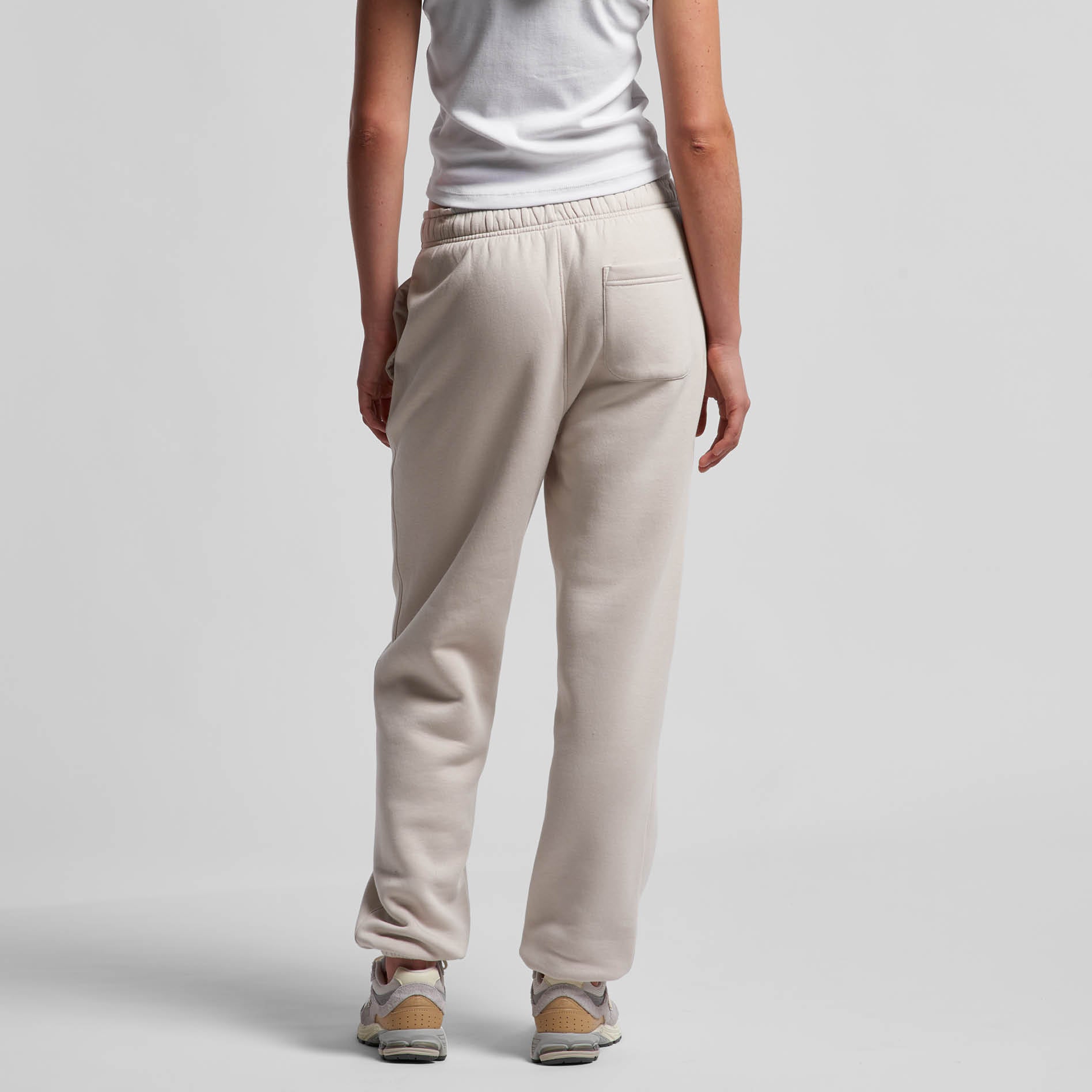 Person wearing bone coloured pants on a white background. Back view. Normalize Neurodivergence.