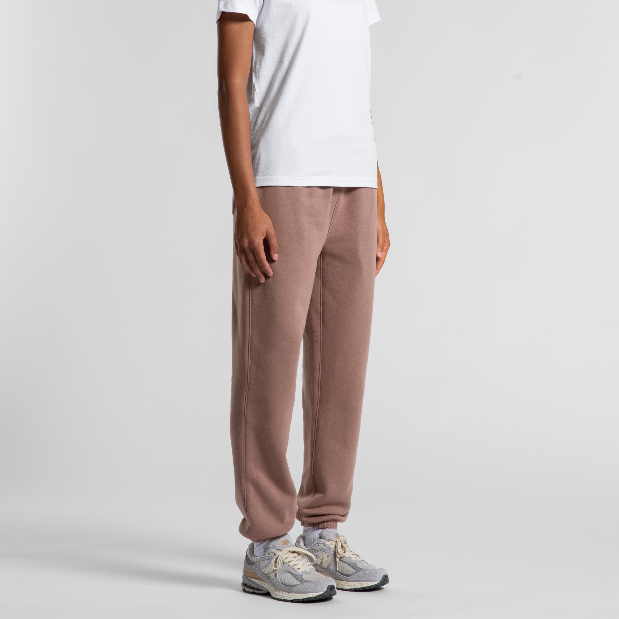 Person wearing hazy pink pants on a white background. Normalize Neurodivergence.